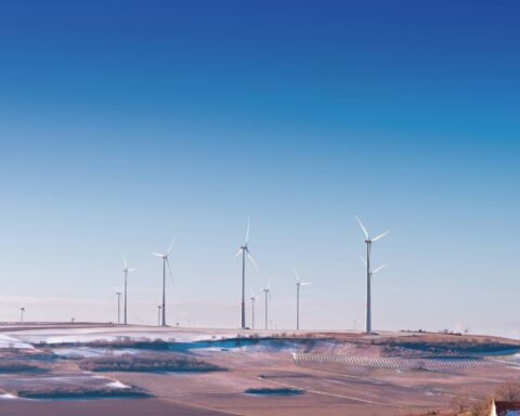 white wind turbine on grey desert under blue and white sky