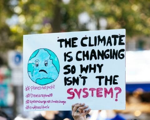 a person holding a sign that says the climate is changing so why isn't