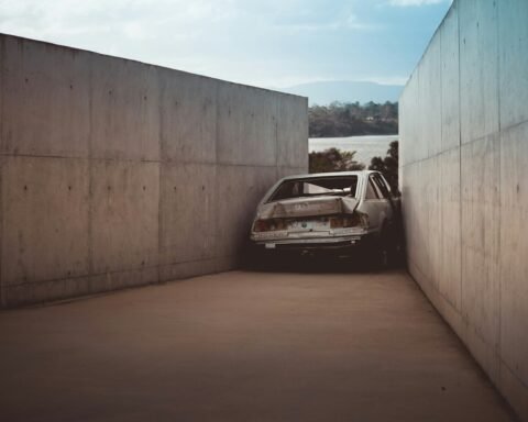 wrecked gray vehicle between concrete walls at daytime