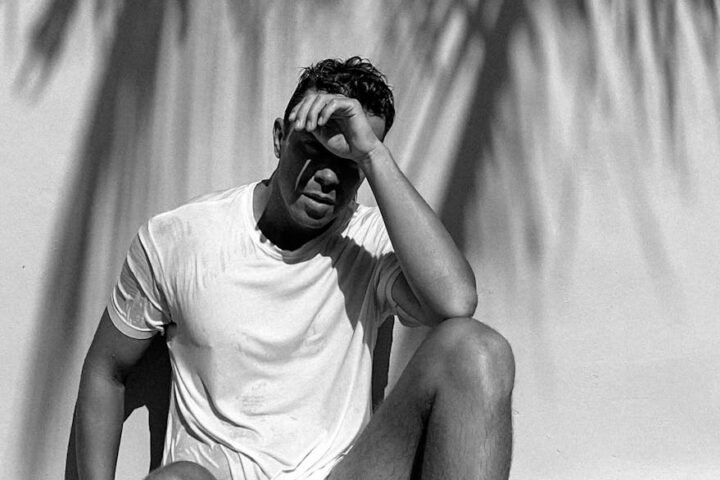 A man sitting on a chair with his hands on his head