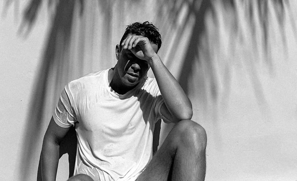 A man sitting on a chair with his hands on his head