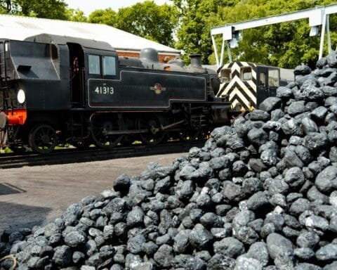 a train on a train track next to a pile of coal