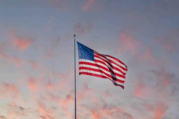 us a flag on pole under cloudy sky