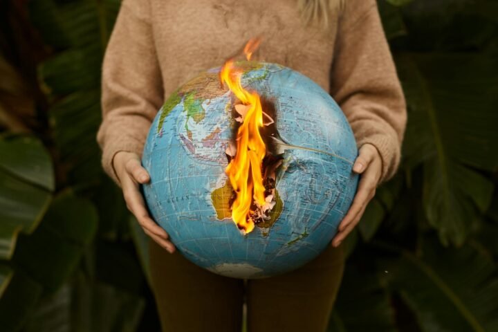 A Person Wearing a Brown Sweater Holding a Burning Globe