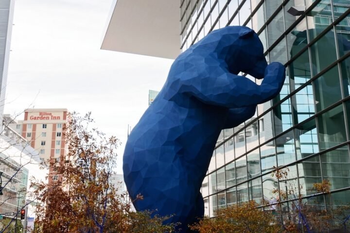 blue bear leaning on glass building