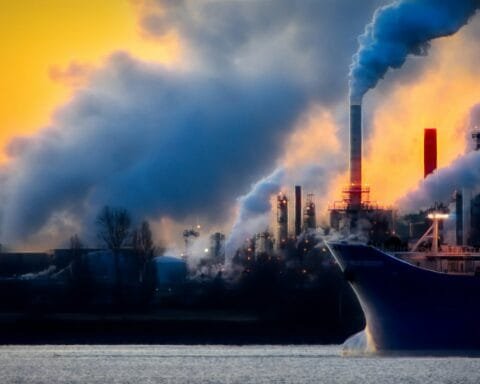a large boat in a body of water near a factory